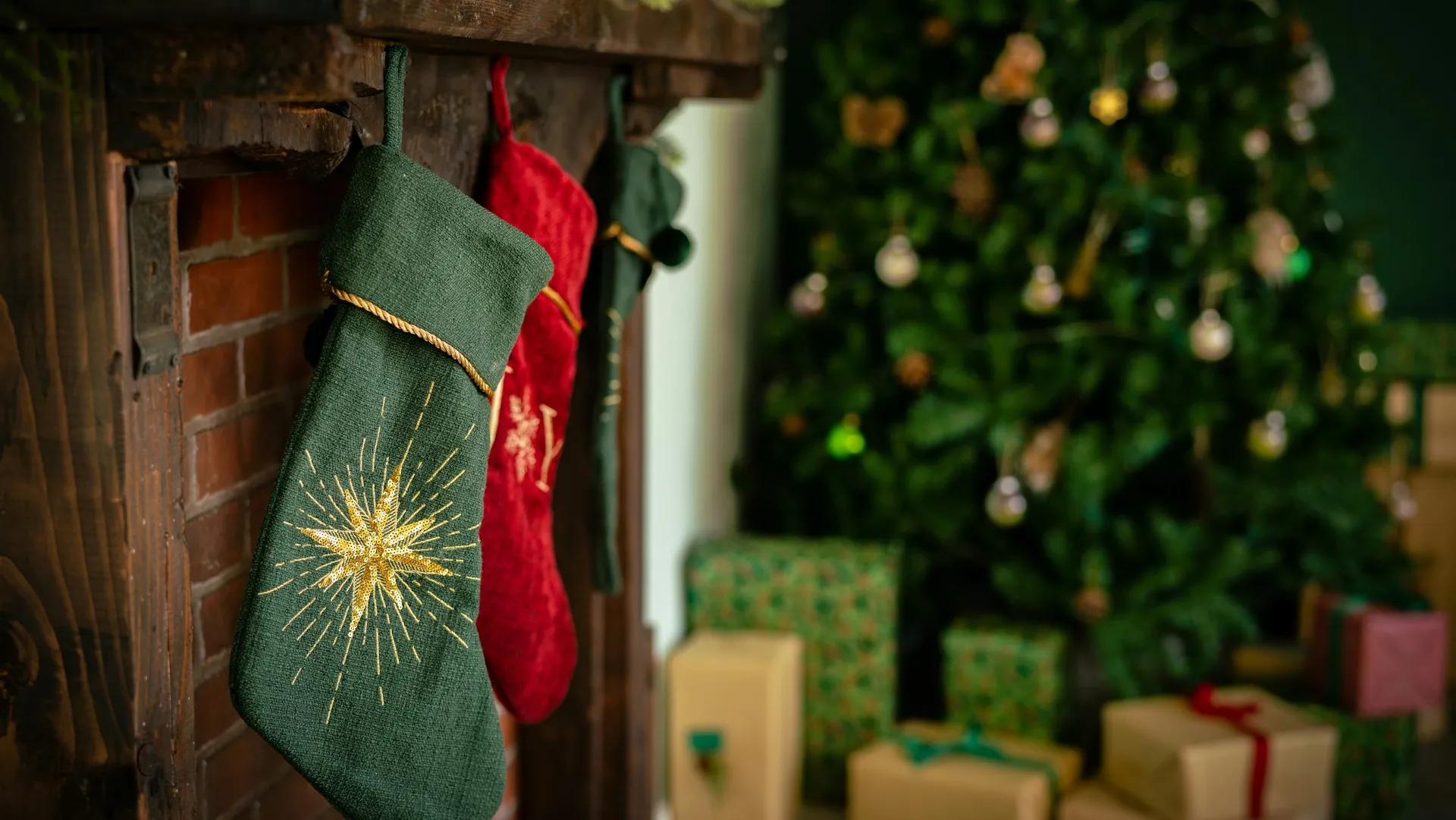 Stockings on a fireplace with a christmas tree in the background